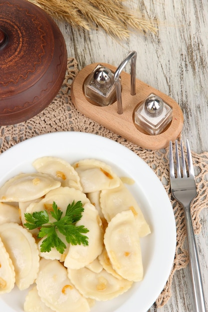 Gnocchi saporiti con cipolla fritta sul piatto bianco su fondo di legno