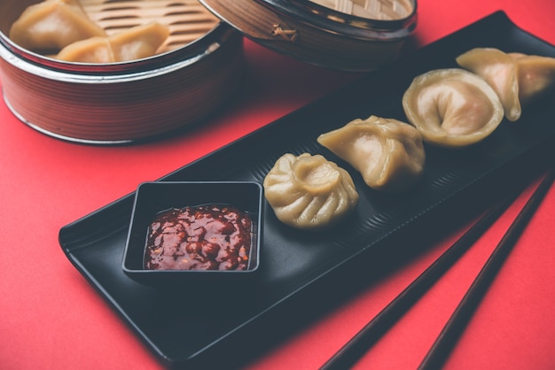 Gnocchi tradizionali momos cibo dal Nepal servito con chutney di pomodoro su sfondo lunatico. Messa a fuoco selettiva