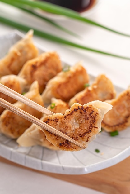 Gnocco di gyoza fritto in padella jiaozi in un piatto con salsa di soia su sfondo bianco della tavola