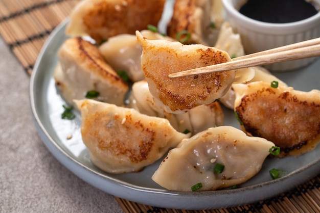 Gnocco di gyoza fritto in padella jiaozi in un piatto con salsa di soia su sfondo grigio della tavola