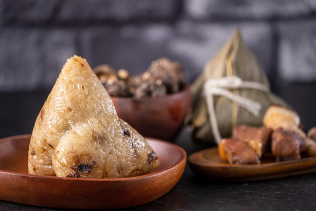 Gnocco di riso zongzi Gnocco di riso cinese zongzi su sfondo di mattoni neri tavolo in ardesia concetto di Dragon Boat Festival cibo tradizionale primo piano