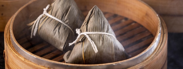 Gnocco di riso zongzi Gnocco di riso cinese zongzi su sfondo di mattoni neri tavolo in ardesia concetto di Dragon Boat Festival cibo tradizionale primo piano