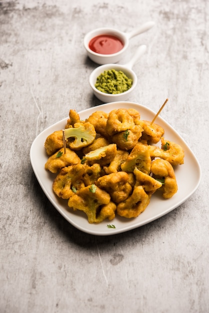 Gobi pakora o Phoolgobi pakoda realizzato con una pastella di ceci fresca imbevuta di cavolfiore e poi fritta in olio. servito con ketchup e chutney di menta. messa a fuoco selettiva