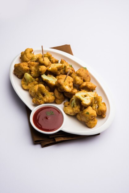 Gobi pakora o Phoolgobi pakoda realizzato con una pastella di ceci fresca imbevuta di cavolfiore e poi fritta in olio. servito con ketchup e chutney di menta. messa a fuoco selettiva