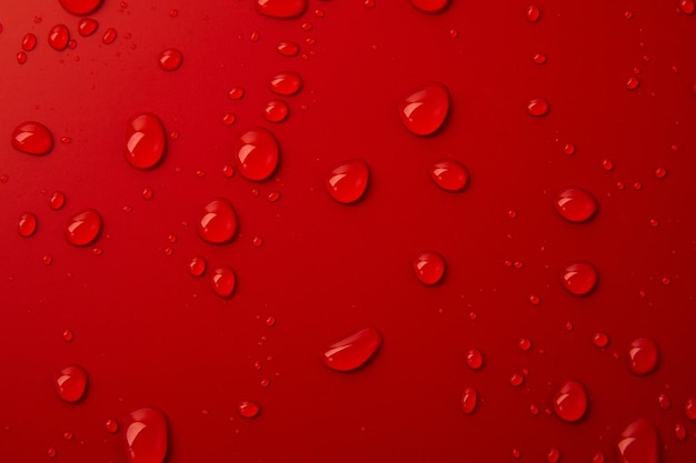 Gocce d'acqua astratte su sfondo rosso macro Bolle da vicino Gocce di liquido cosmetico Modello piatto