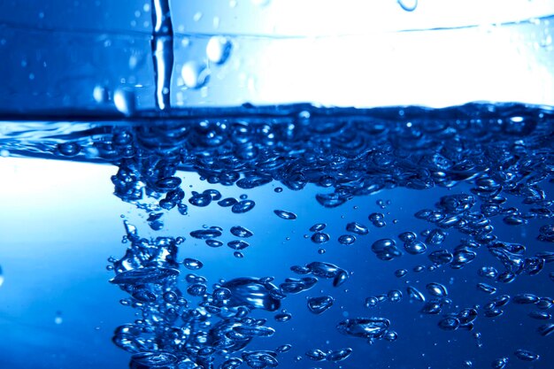 Gocce d'acqua che cadono nell'acqua blu profondo