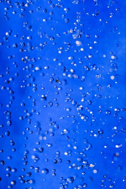 gocce d'acqua e bolle d'aria che salgono su uno sfondo blu