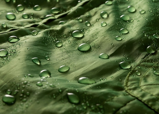 Gocce d'acqua su tessuto a membrana impermeabile. Vista in dettaglio della trama del panno impermeabile verde.