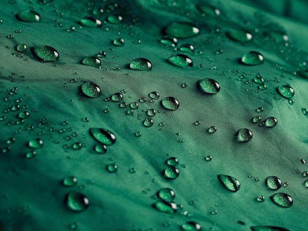 Gocce d'acqua su tessuto a membrana impermeabile. Vista in dettaglio della trama del panno impermeabile verde.
