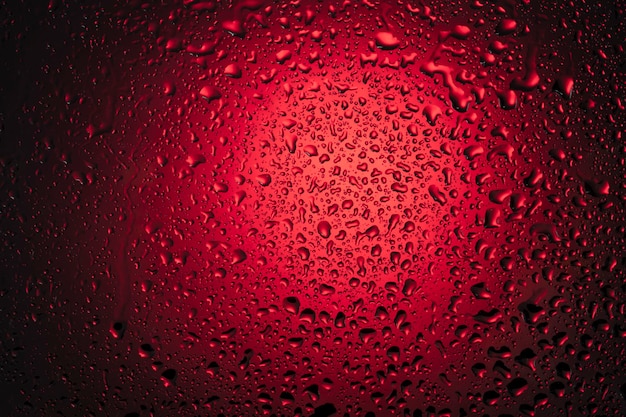 Gocce d'acqua su vetro su sfondo rosso.