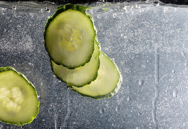 Gocce d'acqua sul cetriolo maturo. Sfondo di verdure fresche con copia spazio per il testo. Concetto vegano e vegetariano.