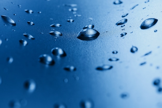 Gocce di acqua pulita sul vetro. Sfondo blu