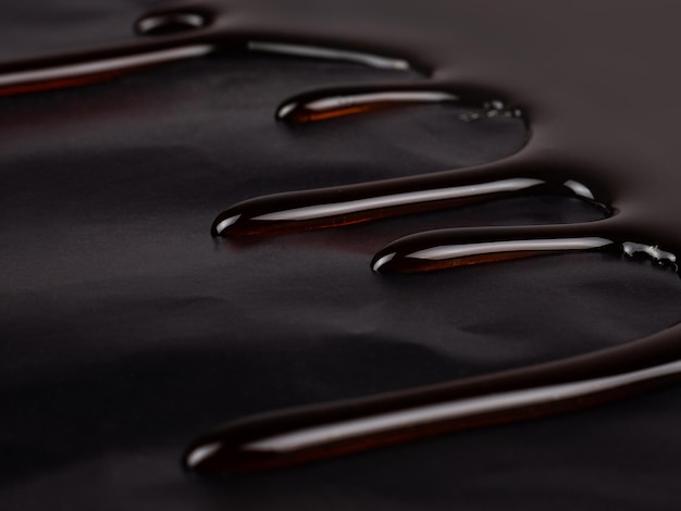 Gocce di caramello al cioccolato su uno sfondo scuro sciroppo di caramello caldo primo piano