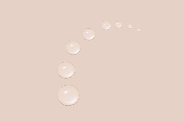 Gocce di gel trasparente o acqua a forma di semicerchio di dimensioni decrescenti su fondo beige