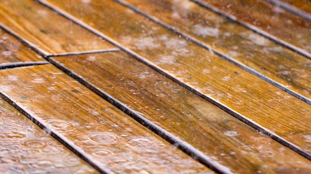 Gocce di pioggia cadono su una terrazza in legno e un ponte vicino alla piscina si chiuda