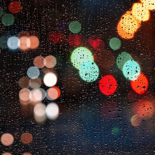 gocce di pioggia sulla finestra e lampioni di notte in città