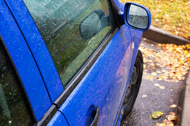 Gocce di pioggia sullo specchietto laterale di un'auto blu