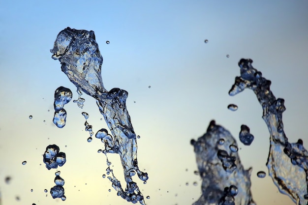 Gocce di una fontana che cade contro il cielo della sera