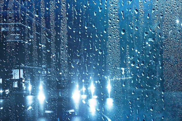 gocce su vetro auto strada pioggia autunno notte / astratto sfondo autunnale in città, traffico automobilistico, viaggio romantico in auto