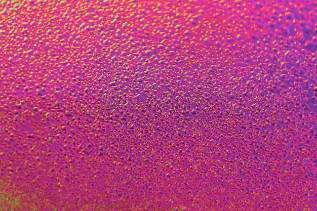 Goccia di pioggia sulla superficie rosa neon. Umore mattutino di primavera. Sfondo luminoso o sfondo. Trama di goccioline d'acqua.