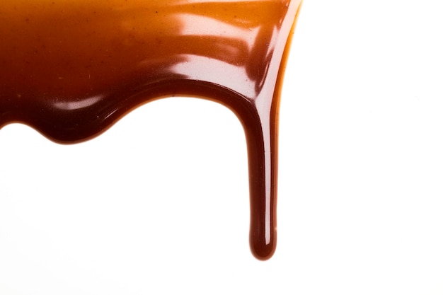 Goccia di salsa al caramello al cioccolato su un semplice fondo bianco