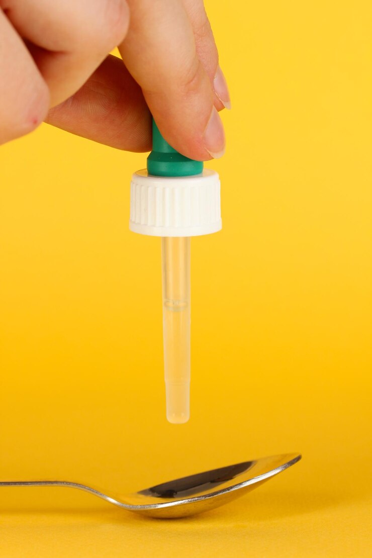 Foto gocciolina medica in cucchiaio su sfondo giallo