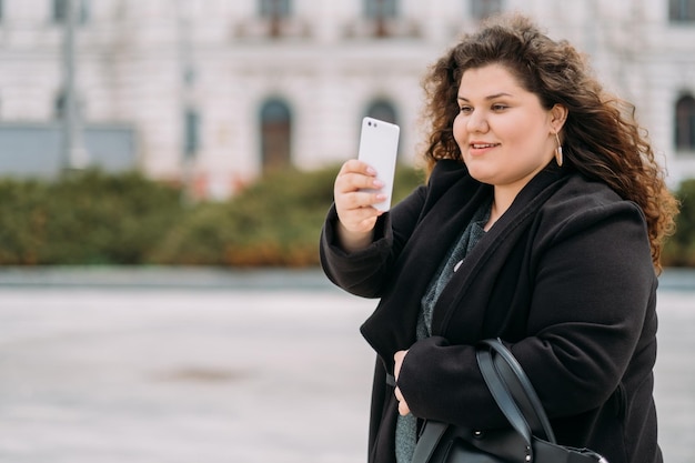 Godendo di camminare felice plus size donna cattura momento stile di vita digitale allegra signora formosa che fa foto