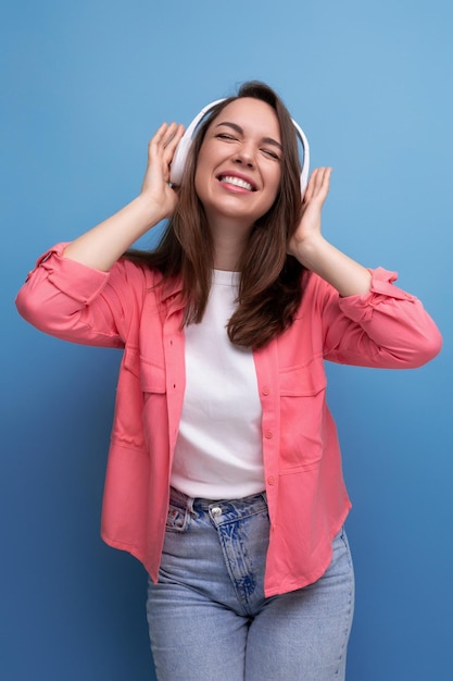 Godendo di una giovane donna bruna con i capelli scuri sotto le spalle in una camicia e jeans con wireless