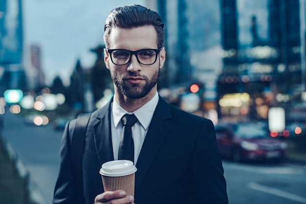 godendo il miglior caffè in città. immagine notturna di un giovane fiducioso in completo completo