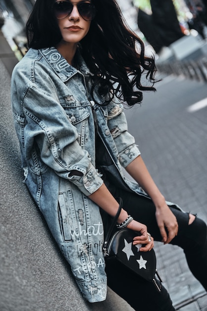 godendo il tempo spensierato all'aperto. attraente giovane donna in giacca di jeans che guarda l'obbiettivo