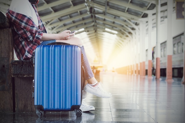 Godere di viaggi. Giovane viaggiatore a piedi con valigia e treno classico a piattaforma ferroviaria. solo viaggio e concetto estivo. filtro dell&#39;annata.