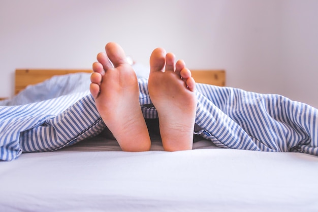 Godersi la mattinata a letto Primo piano dei piedi femminili scoperti nella coperta del letto