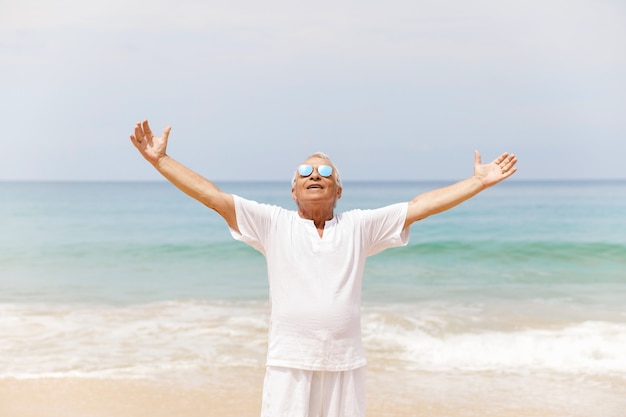 Godersi la pensione. Uomo anziano felice che cammina sulla spiaggia.