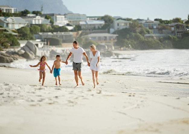 Godersi la perfetta vacanza in famiglia Una giovane famiglia felice che cammina insieme lungo la spiaggia sotto il sole