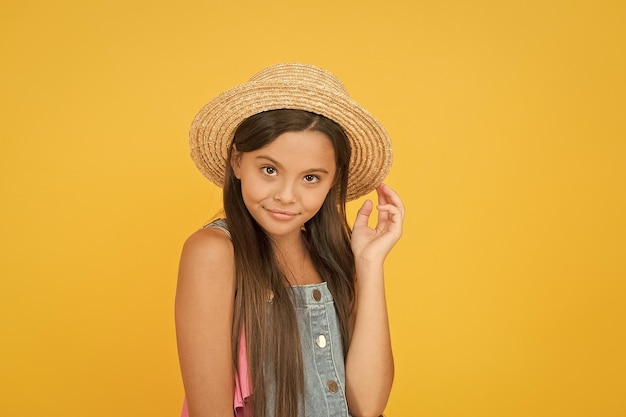 Godersi le vacanze Buone vibrazioni Stile spiaggia Piccola bellezza con cappello di paglia Vestito fantasia Moda estiva per ragazze adolescenti Vacanze estive Ritratto di ragazza allegra felice in cappello estivo sfondo giallo