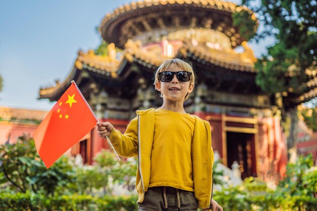 Godersi le vacanze in Cina Ragazzo con bandiera nazionale cinese nella Città Proibita Viaggio in Cina con il concetto di bambini Transito gratuito 72 ore 144 ore in Cina