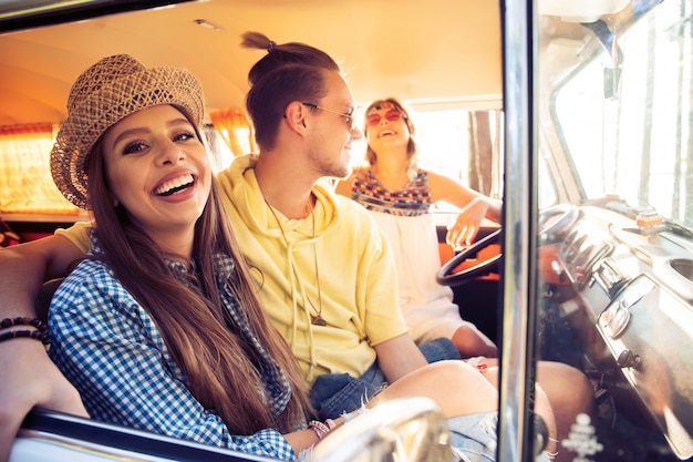 Godersi un fantastico viaggio con gli amici. Gruppo di giovani allegri divertendosi seduti all'interno del minivan.