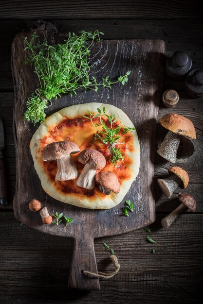 Goditi la tua pizza rustica su un vecchio tavolo di legno