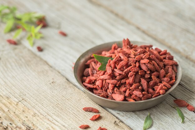 Goji in ciotola sulla tavola di legno.