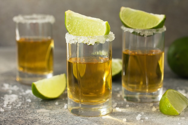 Gold Tequila Mexican Gold Tequila shot con lime e sale su un piano di lavoro in cemento chiaro in pietra