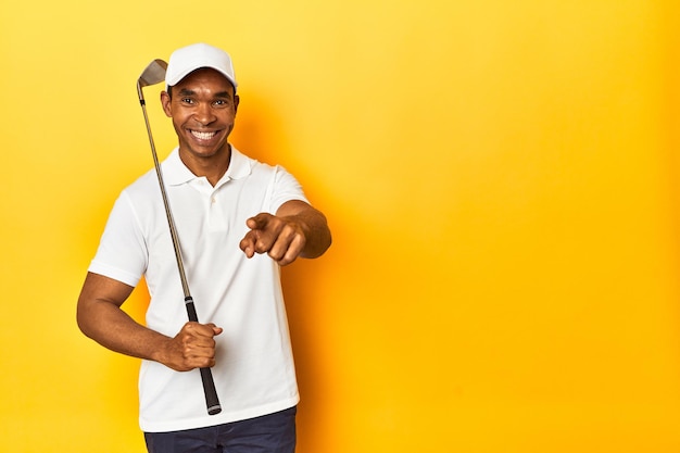 Golfista afroamericano in azione posato in uno studio a sfondo giallo