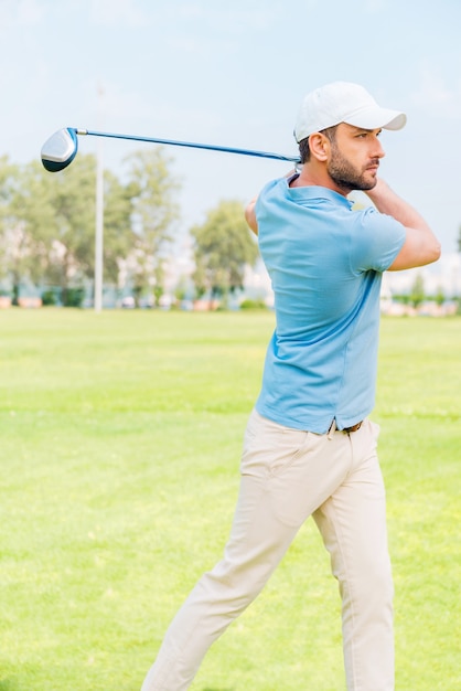 Golfista professionista. Fiducioso giovane che gioca a golf mentre si sta in piedi sul campo da golf