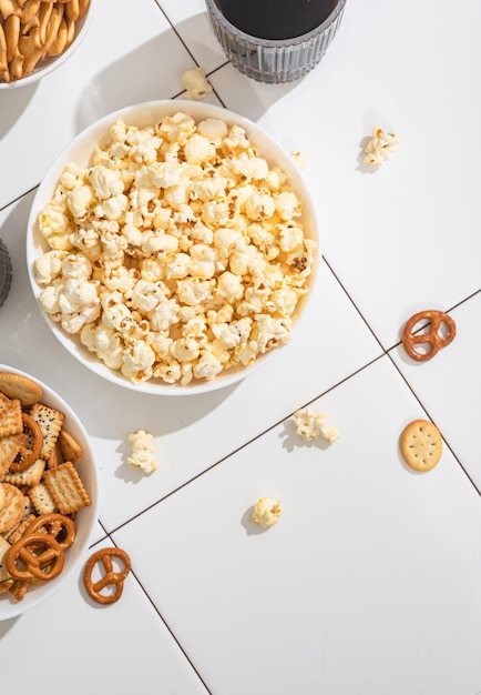 Golosità fatte in casa fast food una ciotola con cracker di popcorn e biscotti su un tavolo bianco