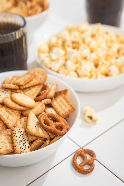 Golosità fatte in casa fast food una ciotola con cracker di popcorn e biscotti su un tavolo bianco