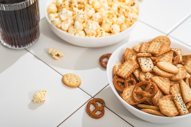 Golosità fatte in casa fast food una ciotola con cracker di popcorn e biscotti su un tavolo bianco