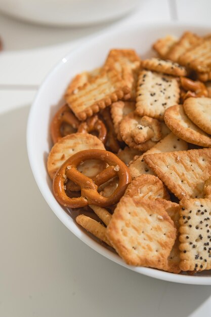 Golosità fatte in casa fast food una ciotola con cracker di popcorn e biscotti su un tavolo bianco