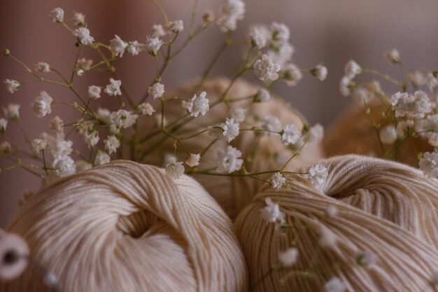 gomitolo di filato beige per lavorare a maglia primo piano su uno sfondo di fiori pastello