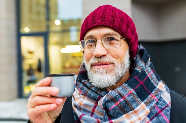 Goog cercando uomo maturo bere tè caldo in una strada di città in inverno