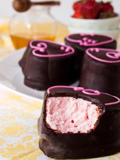 Gourmet cioccolato ricoperti di marshmallow alla fragola su sfondo bianco.