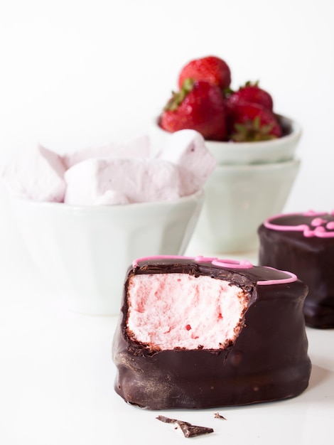 Gourmet cioccolato ricoperti di marshmallow alla fragola su sfondo bianco.